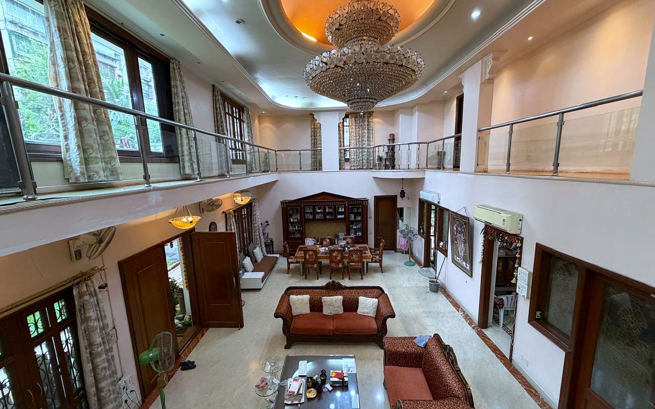 The double-height living hall of an Urban Nest PG property in Mumbai, with a mezzanine gallery and windows on both levels